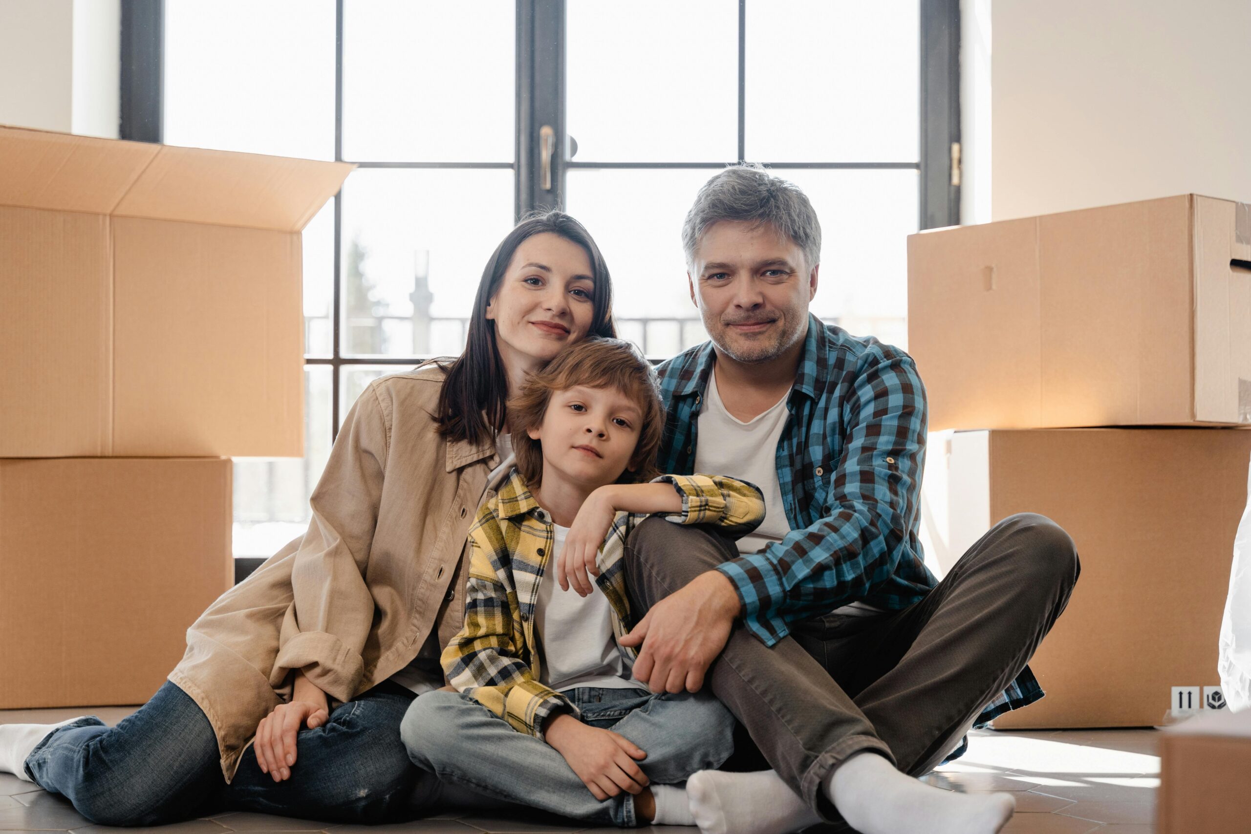 A family sitting together in their new home with moving boxes around them, having sold their previous house fast in Raytown MO